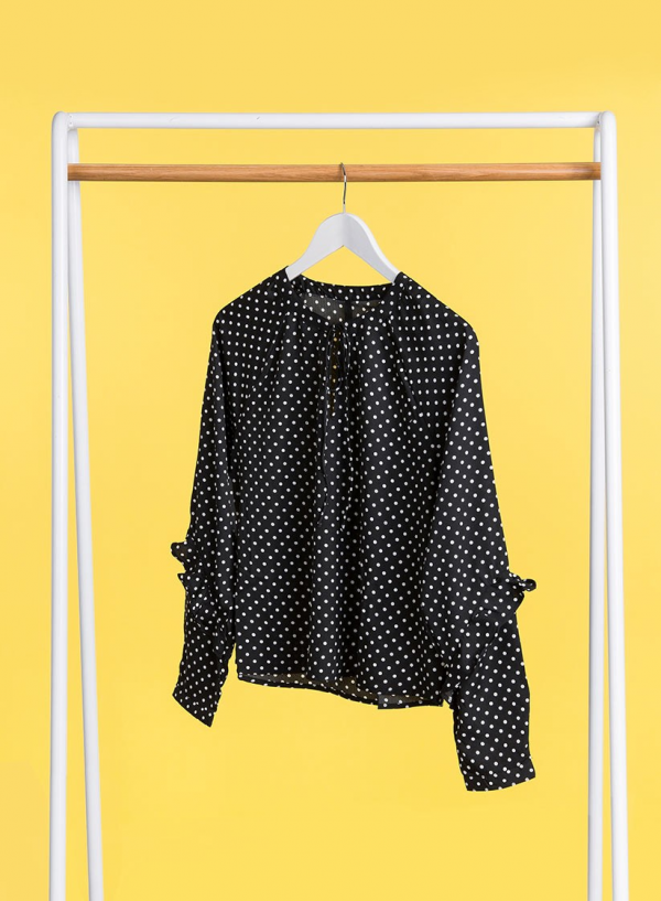 Frente exposta em cabide de blusa às bolinhas com folhos em preto da Tiffosi
